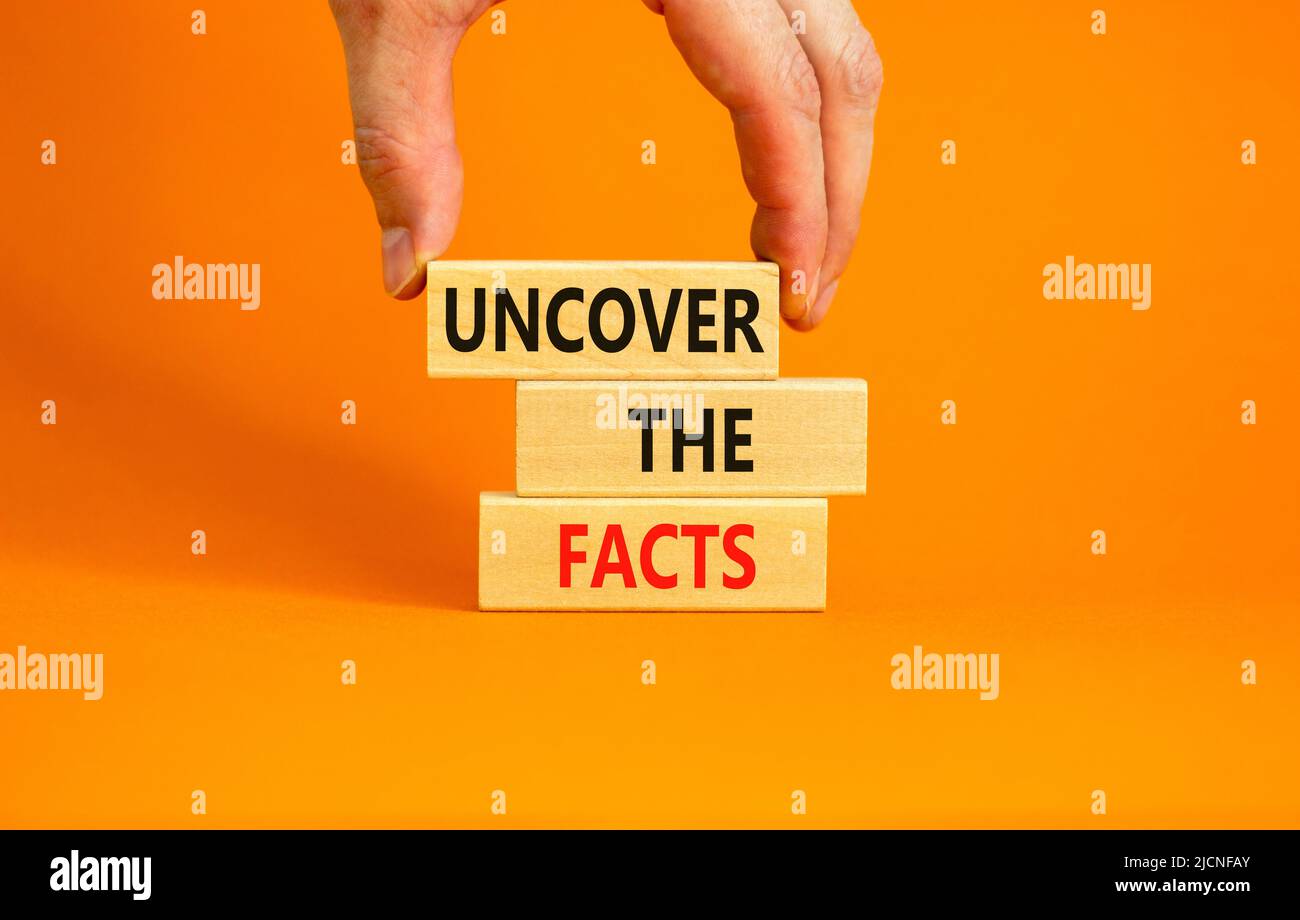 Découvrez le symbole des faits. Les mots-concepts découvrent les faits sur des blocs de bois sur un magnifique fond orange de table. Main d'homme d'affaires. Affaires a Banque D'Images
