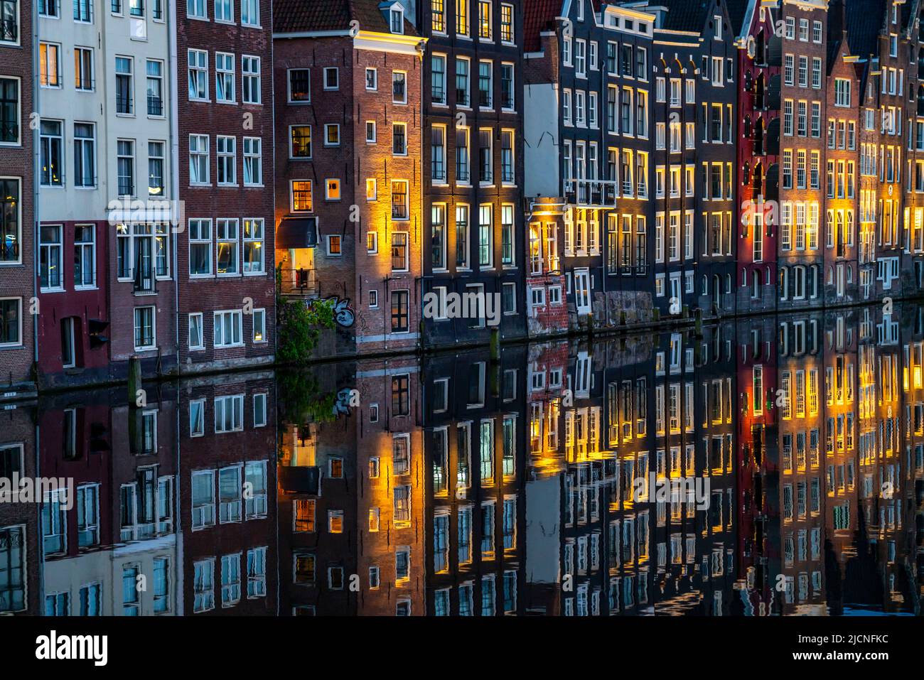 Maisons de canal sur le Damrak, dans le centre de la vieille ville d'Amsterdam, port, point de départ de nombreuses visites de canal, soirée, pays-Bas, Banque D'Images