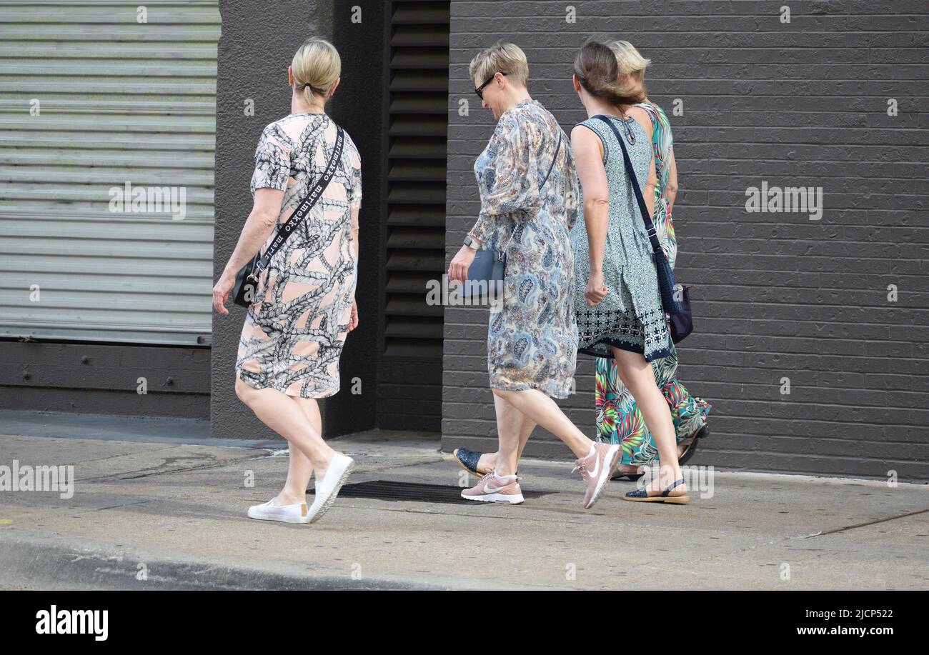 Quatre femmes marchant sur une promenade du côté de la ville, trois femmes portant de longues robes Banque D'Images