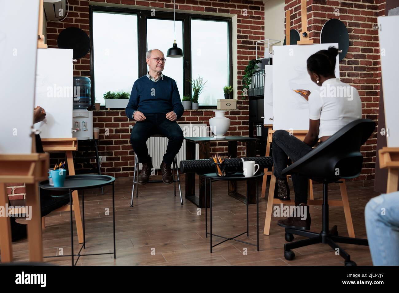 Homme enseignant expliquant la technique de l'art à une équipe diversifiée pendant le cours d'art. Les personnes multiethniques dessinant un vase croquis sur toile à l'aide d'un crayon graphique travaillant sur l'illustration artistique. Concept de passe-temps créatif Banque D'Images