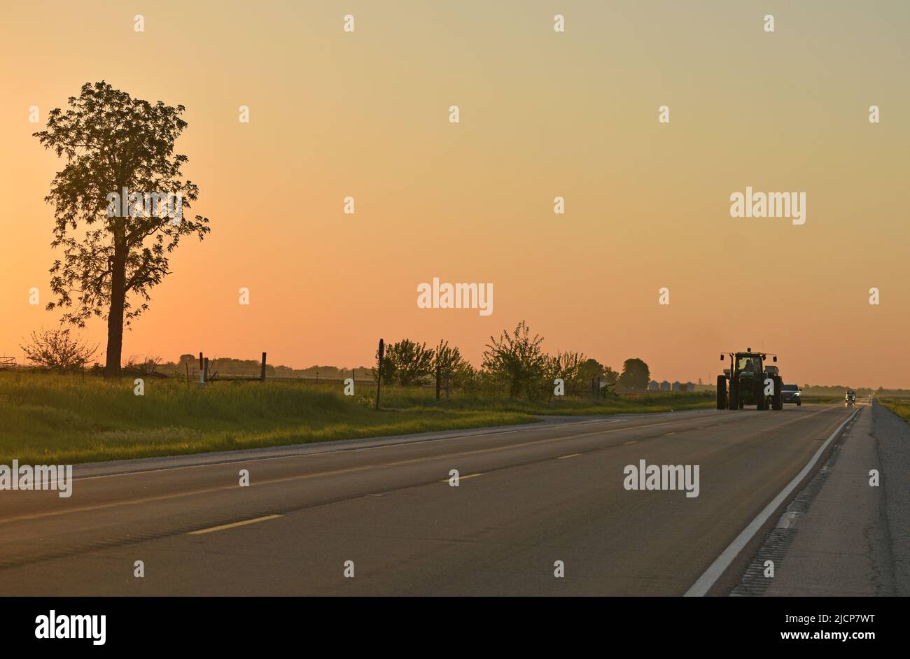 Un grand tracteur John Deere se trouvant à l'ouest sur la U.S. Highway 36 dans le comté de Douglas, Illinois (centre-est de l'Illinois) au lever du soleil Banque D'Images