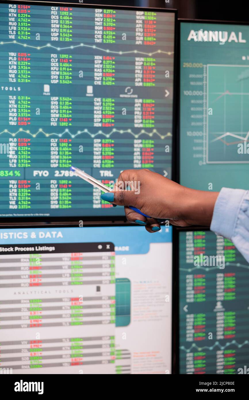 Gros plan de forex bourse négociant femme pointant à l'écran montrant des données de trading en temps réel. Un analyste financier signale les changements de bénéfices affichés dans l'espace de travail du bureau. Banque D'Images