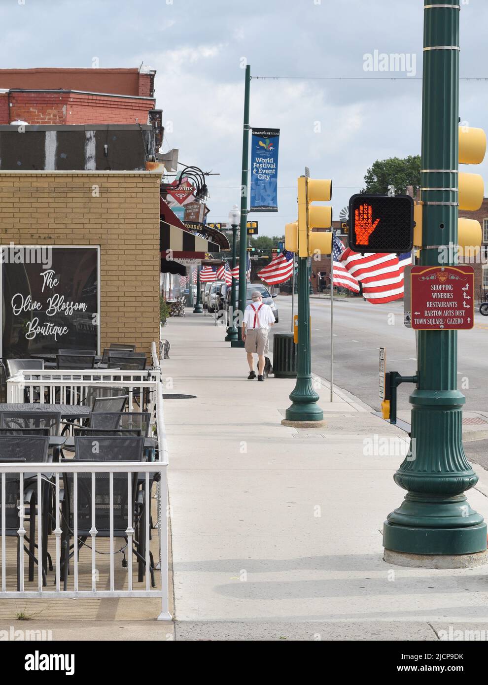 Un homme plus âgé qui marche son chien devant les drapeaux américains qui ornent main Street dans le centre-ville historique de Grapevine, Texas, le week-end du Memorial Day Banque D'Images