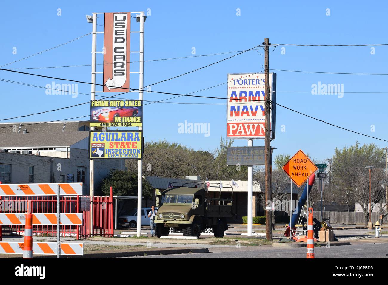 Route en construction avec des panneaux au-dessus de la publicité des voitures d'occasion et un magasin de la Marine de l'Armée de terre et de la boutique de pion Banque D'Images