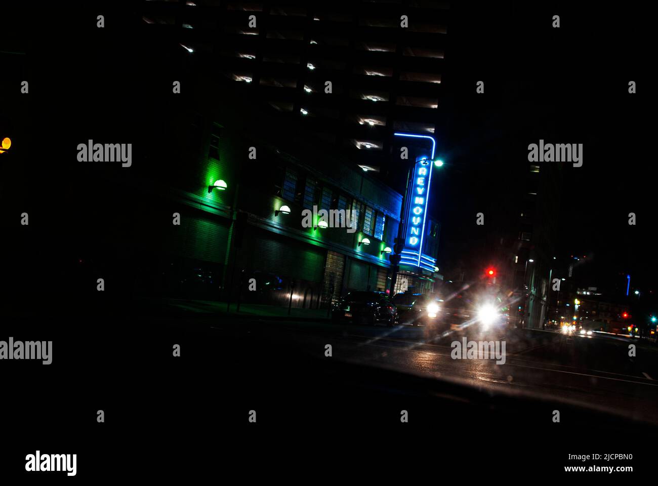 La nuit, des phares de voiture viennent devant la gare routière Greyhound dans le centre-ville de Dallas, Texas Banque D'Images