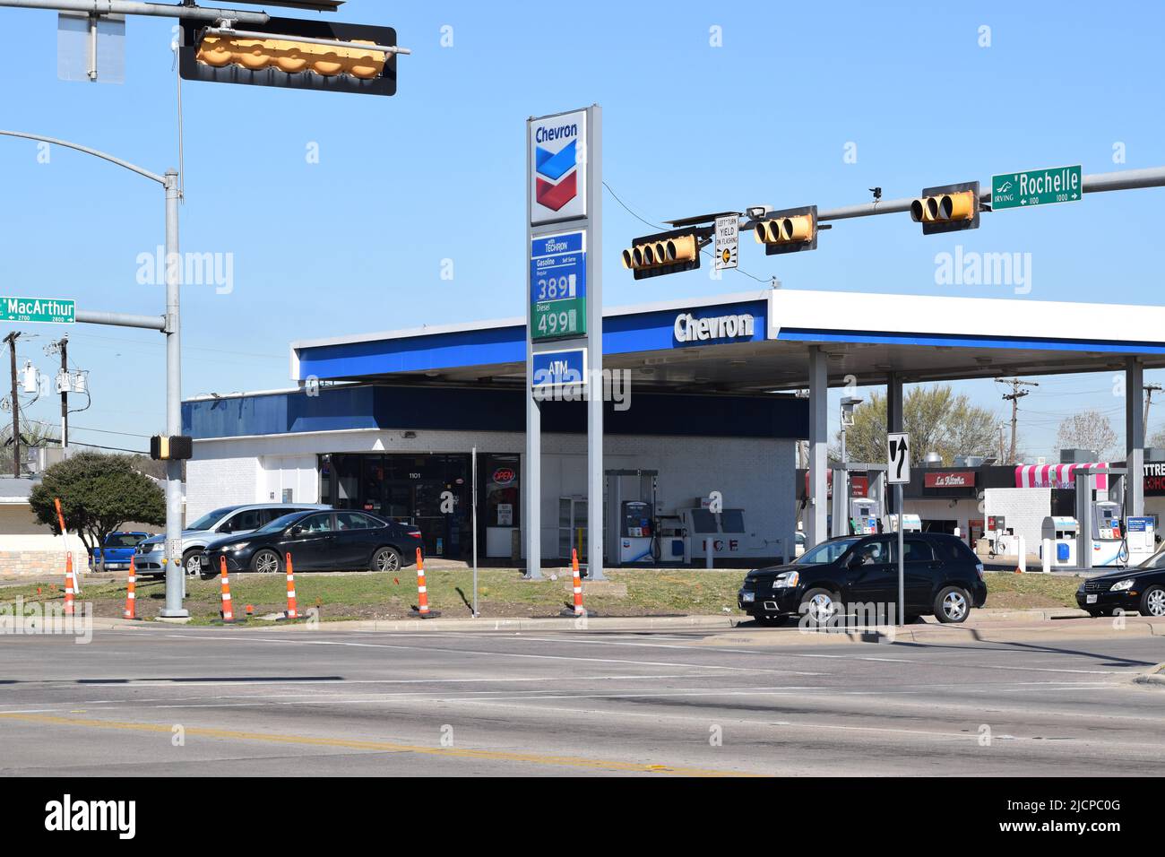 Les voitures s'arrêtaient au feu de circulation avec une station-service Chevron en arrière-plan Banque D'Images