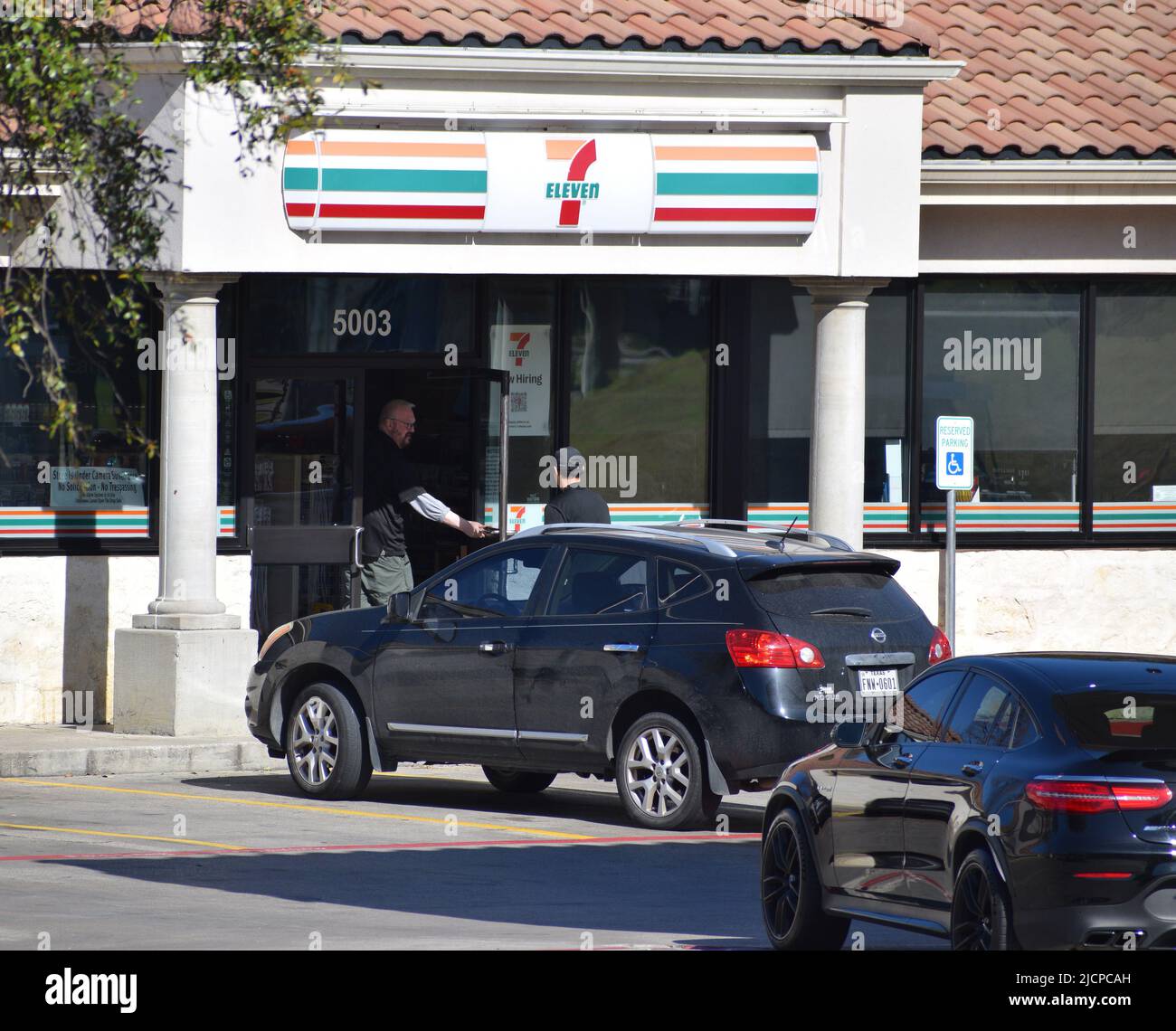 Un homme blanc tenant une porte ouverte pour un homme hispanique, montrant la bonté, à un 7-11 à Irving, Texas Banque D'Images