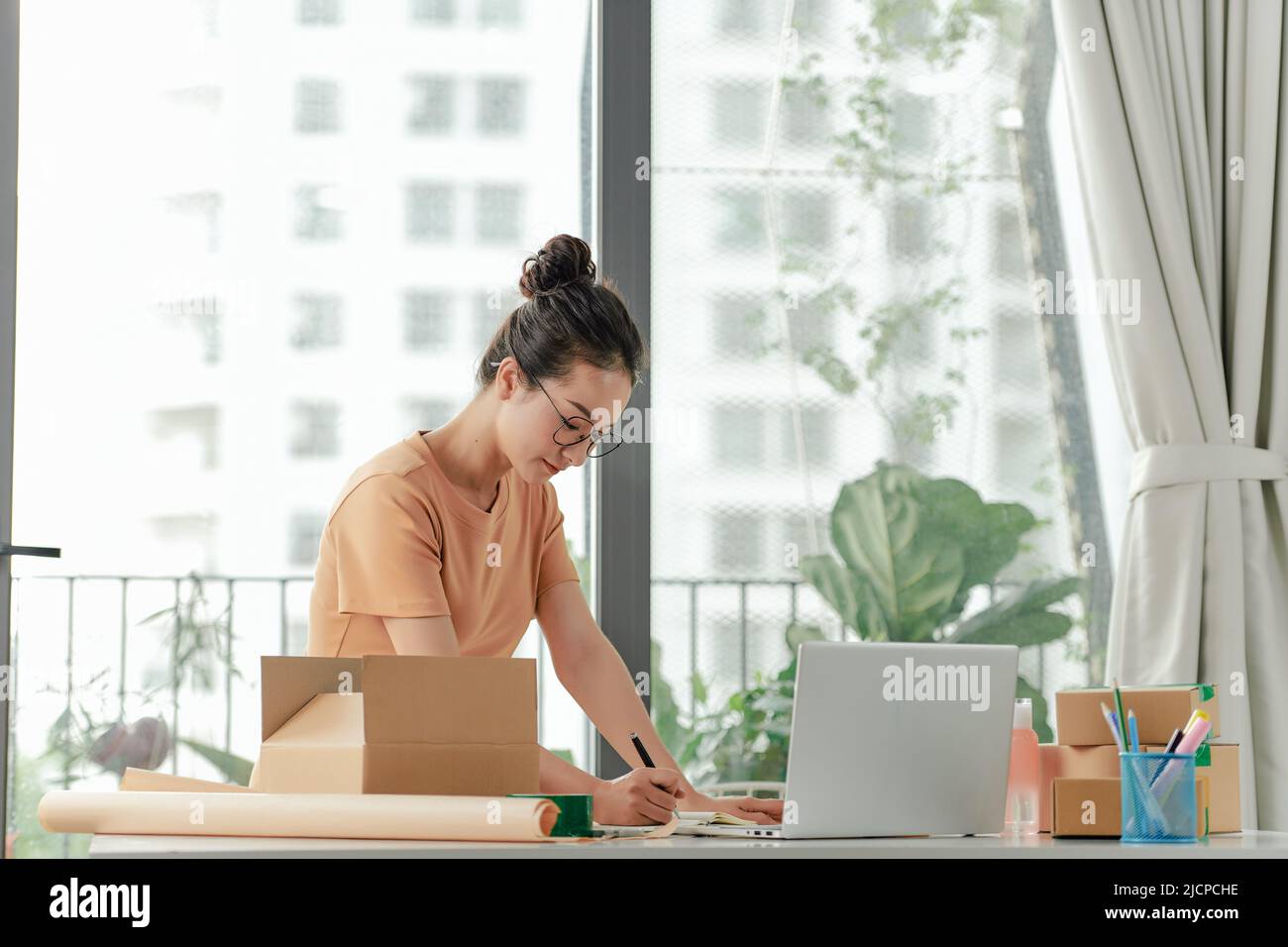 femme vérifiant le bon de commande dans l'ordinateur portable et écrire la livraison sur la boîte de l'emballage Banque D'Images