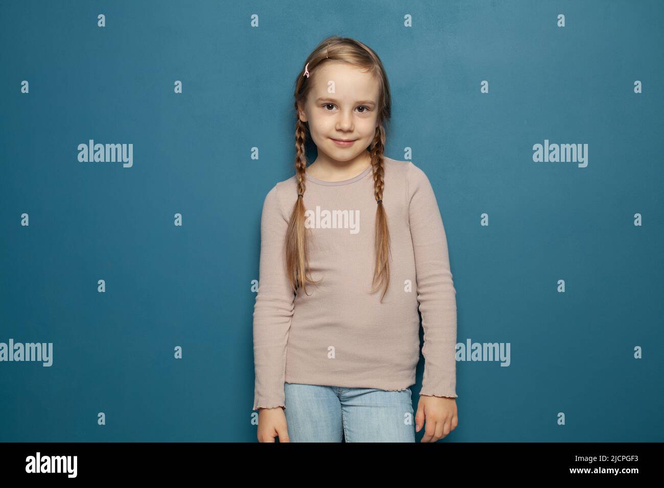 Petit enfant mignon enfant fille de 7-8 ans portant un t-shirt sur fond bleu, enfants portrait studio. Concept de l'enfance. Banque D'Images