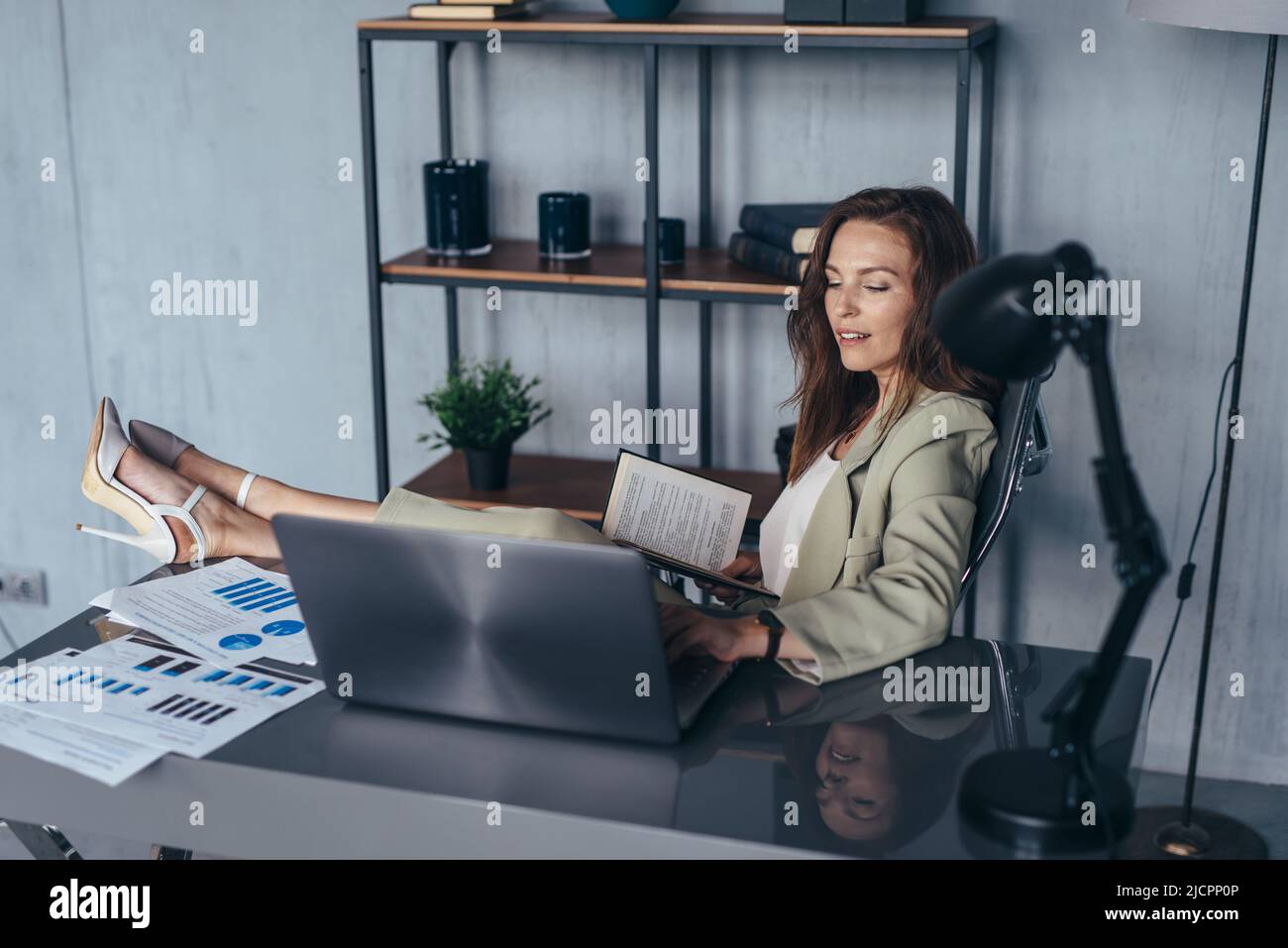 Femme travaillant dans un bureau avec ses pieds sur sa table. Banque D'Images