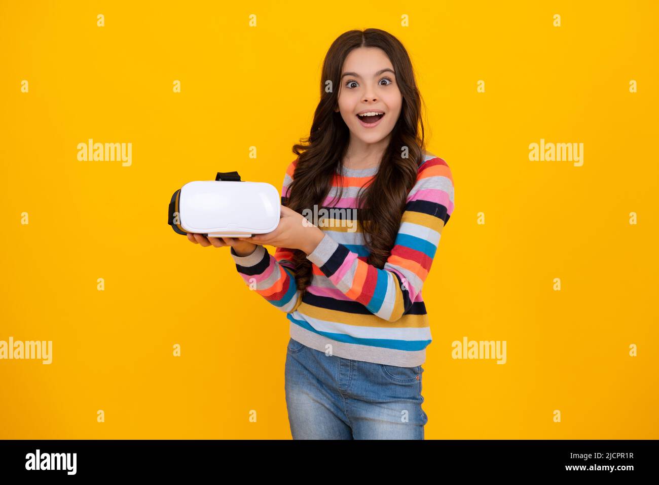 Une jeune fille choquée dans le casque de réalité virtuelle, réalité VR. Isolé en studio, portrait. Concept de technologies modernes. Adolescent heureux, positif et Banque D'Images