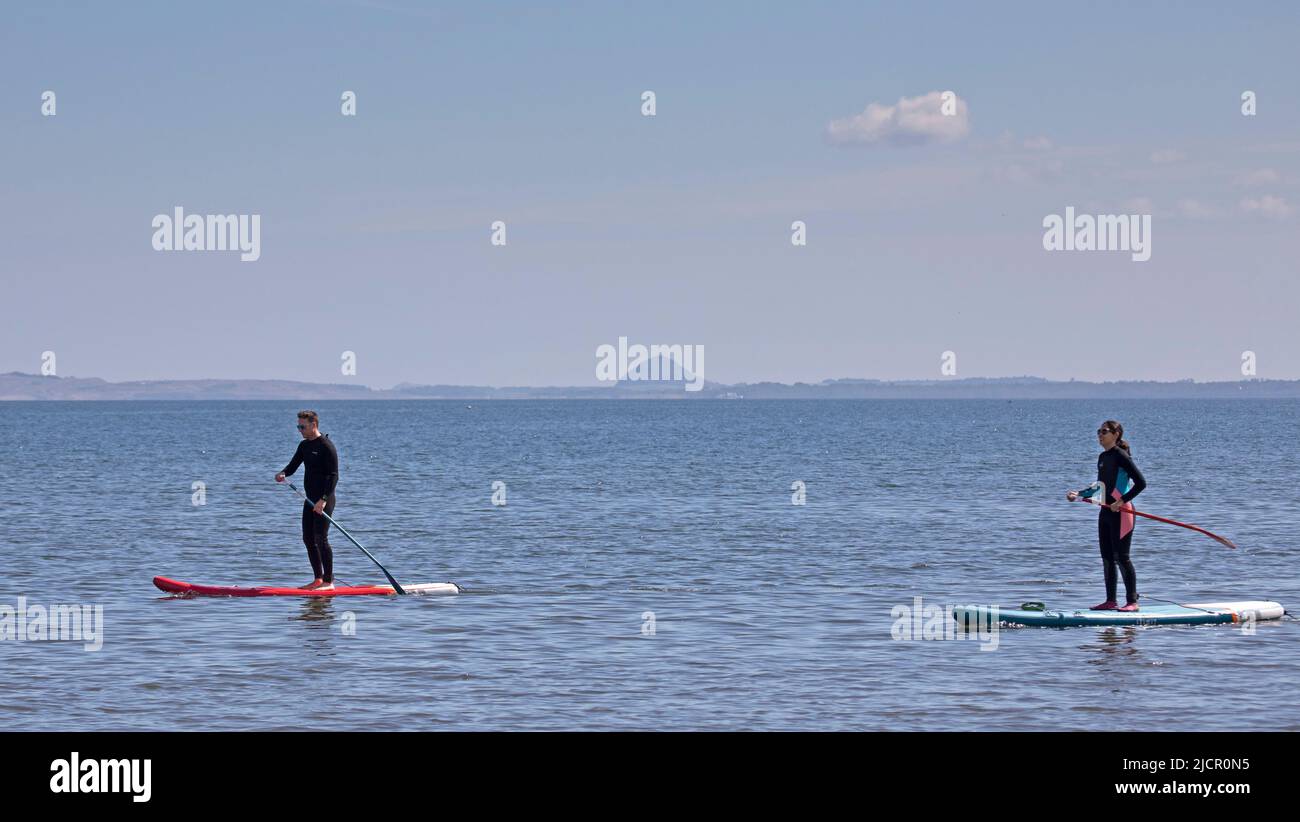 Portobello, Édimbourg, Écosse, Royaume-Uni. 15.06.2022. Vague de chaleur attirant les paddleboarders sur le Firth of Forth, il a été quelques semaines depuis que tout s'est aventuré dehors en raison des récentes conditions froides nuageux. La température de ce matin de 18 degrés a amené quelques-uns dehors pour l'exercice. Photo : paddleboardeurs mâles et femelles avec Berwick Law en arrière-plan. Credit: Scottiscreative/alamy Live news. Banque D'Images