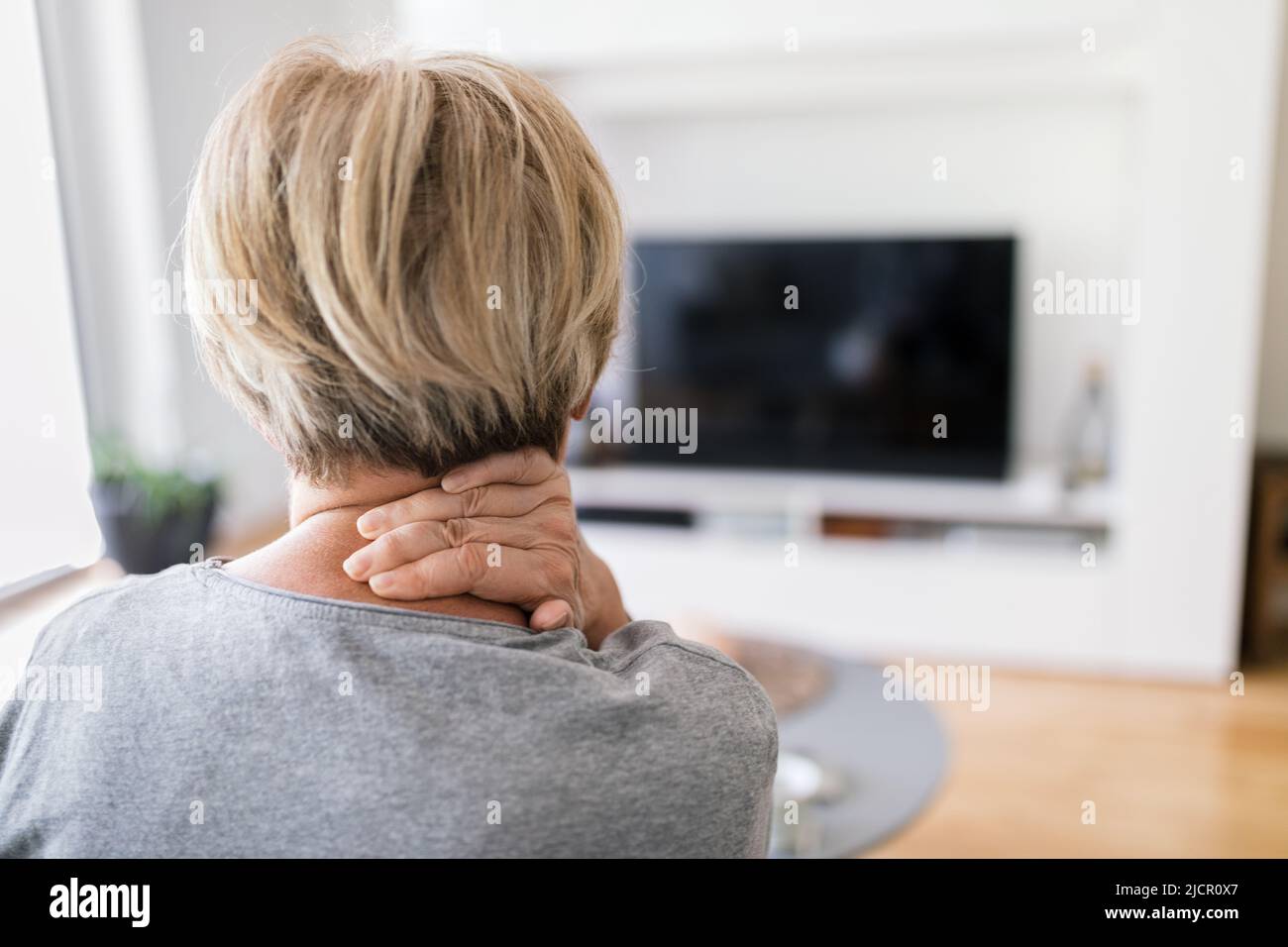 Femme âgée dans le salon avec douleurs au cou Banque D'Images