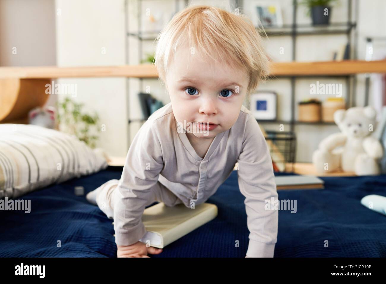 Portrait d'un adorable tout-petit avec des cheveux blonds rampant sur son lit pendant son temps actif à la maison Banque D'Images