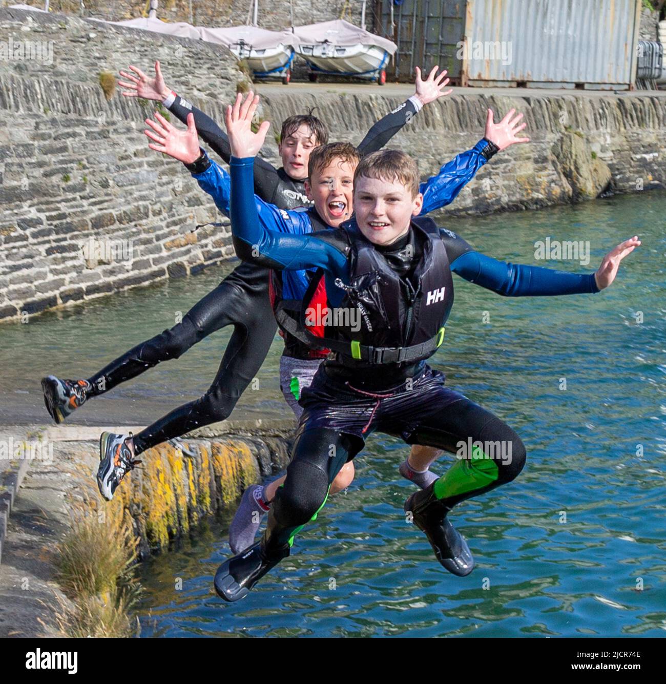 Les jeunes garçons sautent d'un quai dans la mer pendant les vacances d'été ou d'été Banque D'Images