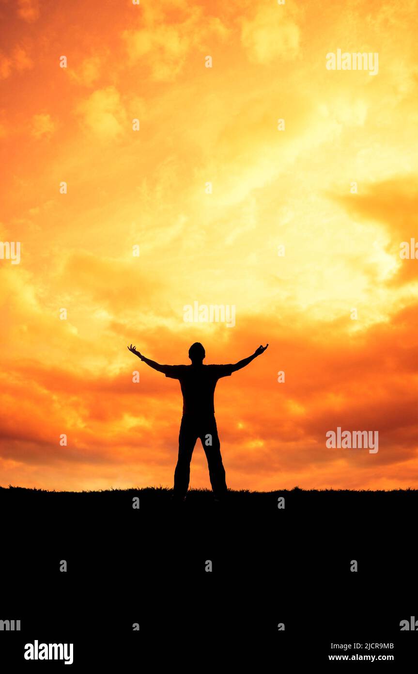 silhouette d'homme aux bras ouverts devant un ciel de coucher de soleil Banque D'Images