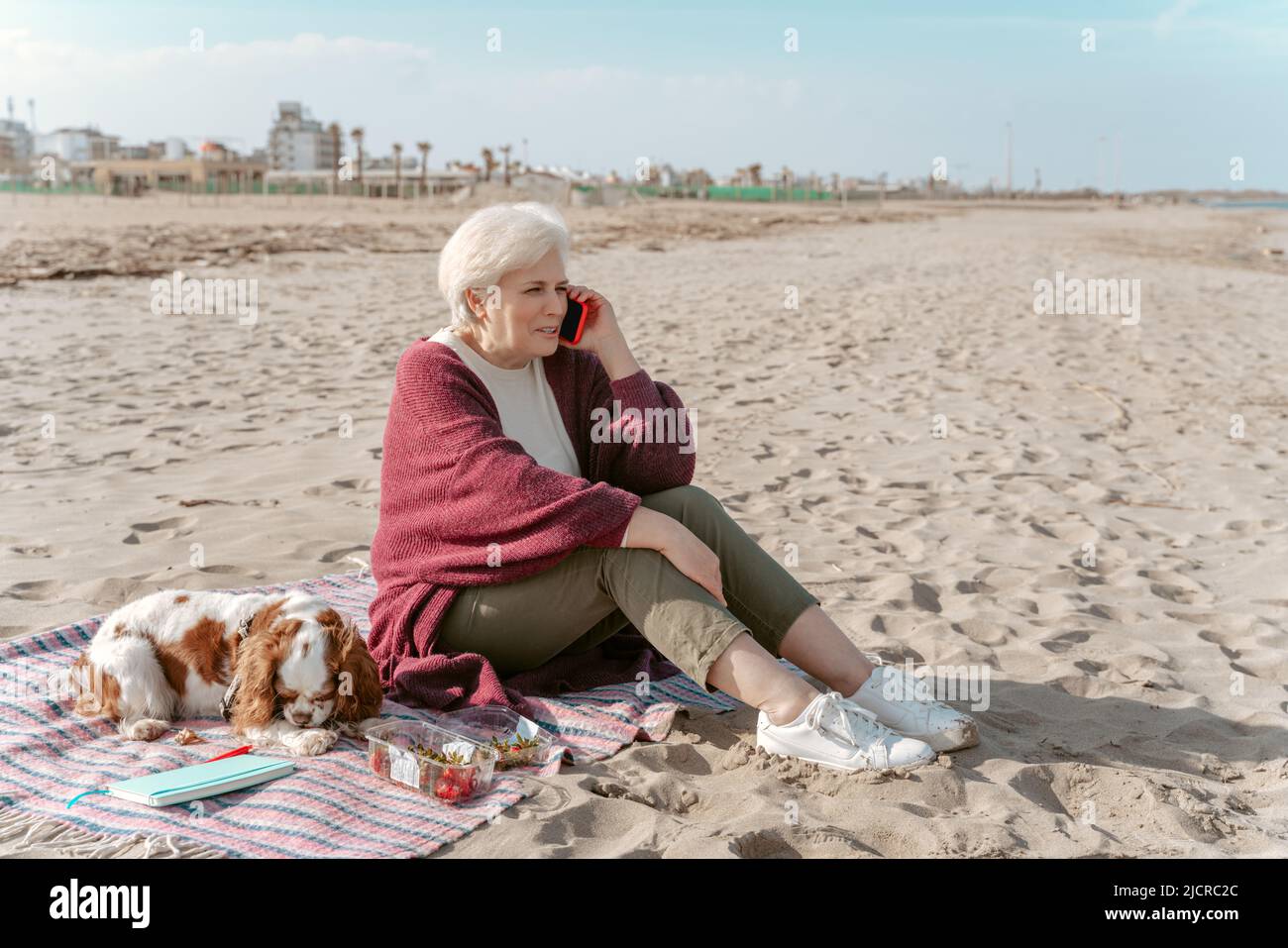 Une femme aux cheveux gris qui parle sur le smartphone au bord de la mer Banque D'Images