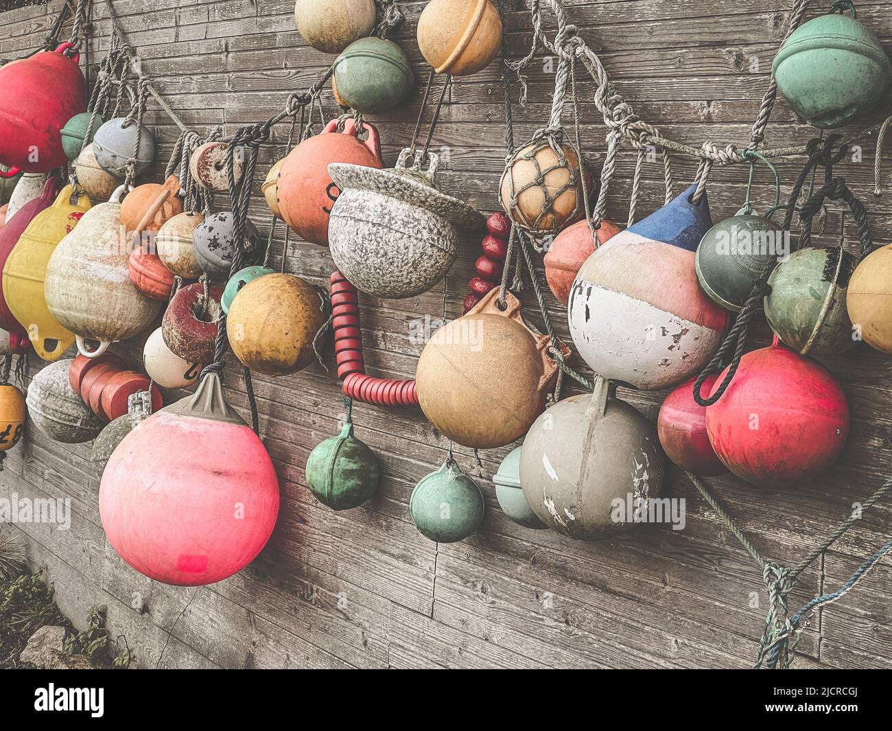 Beaucoup de bouées multicolores accrochées comme décoration sur un mur en bois dans un jardin Banque D'Images