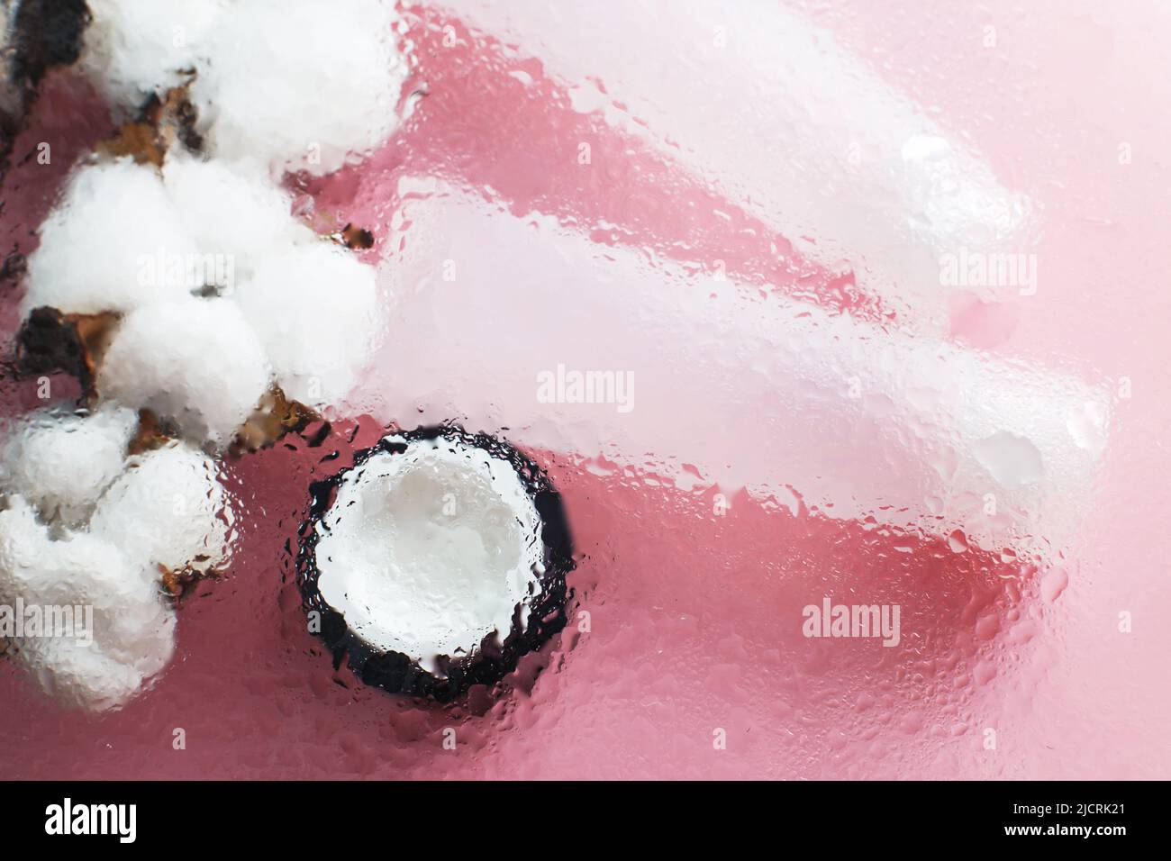 Concept de produits hydratants naturels pour les soins de la peau. Crème pour le visage et les mains sous une surface en verre avec de l'eau sur fond rose. Banque D'Images