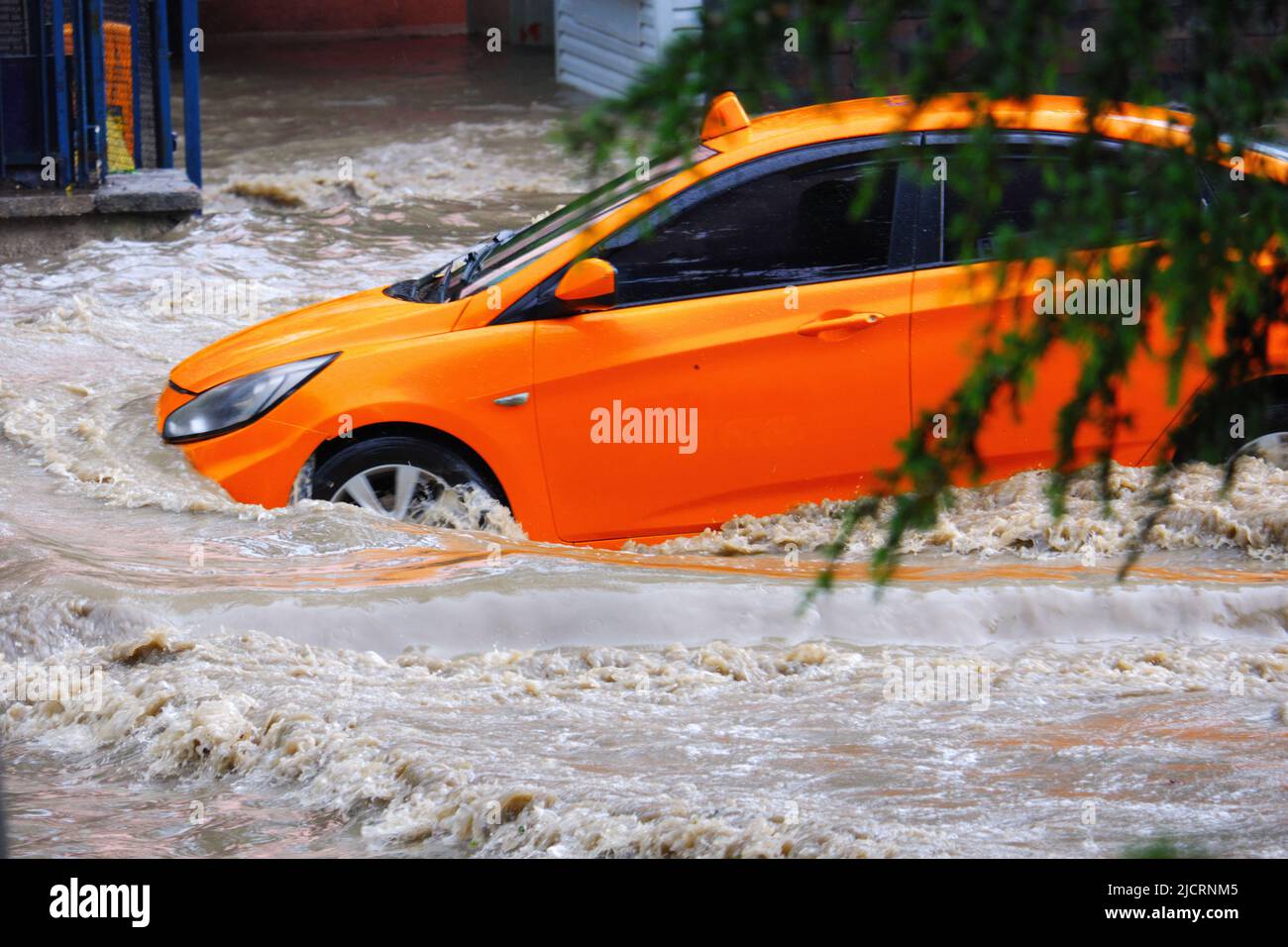 Taxi se déplaçant dans les eaux sales d'inondation dans la route Banque D'Images