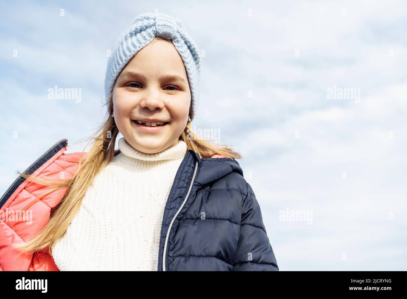 Portrait d'une fille de 8 ans contre le ciel. Banque D'Images