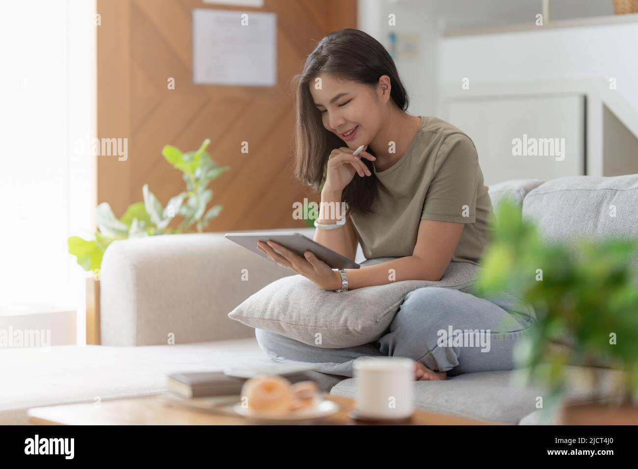 Portrait d'une jeune femme asiatique utilisant les réseaux sociaux pour discuter sur tablette numérique. Style de vie, shopping en ligne, détente sur le canapé. Banque D'Images
