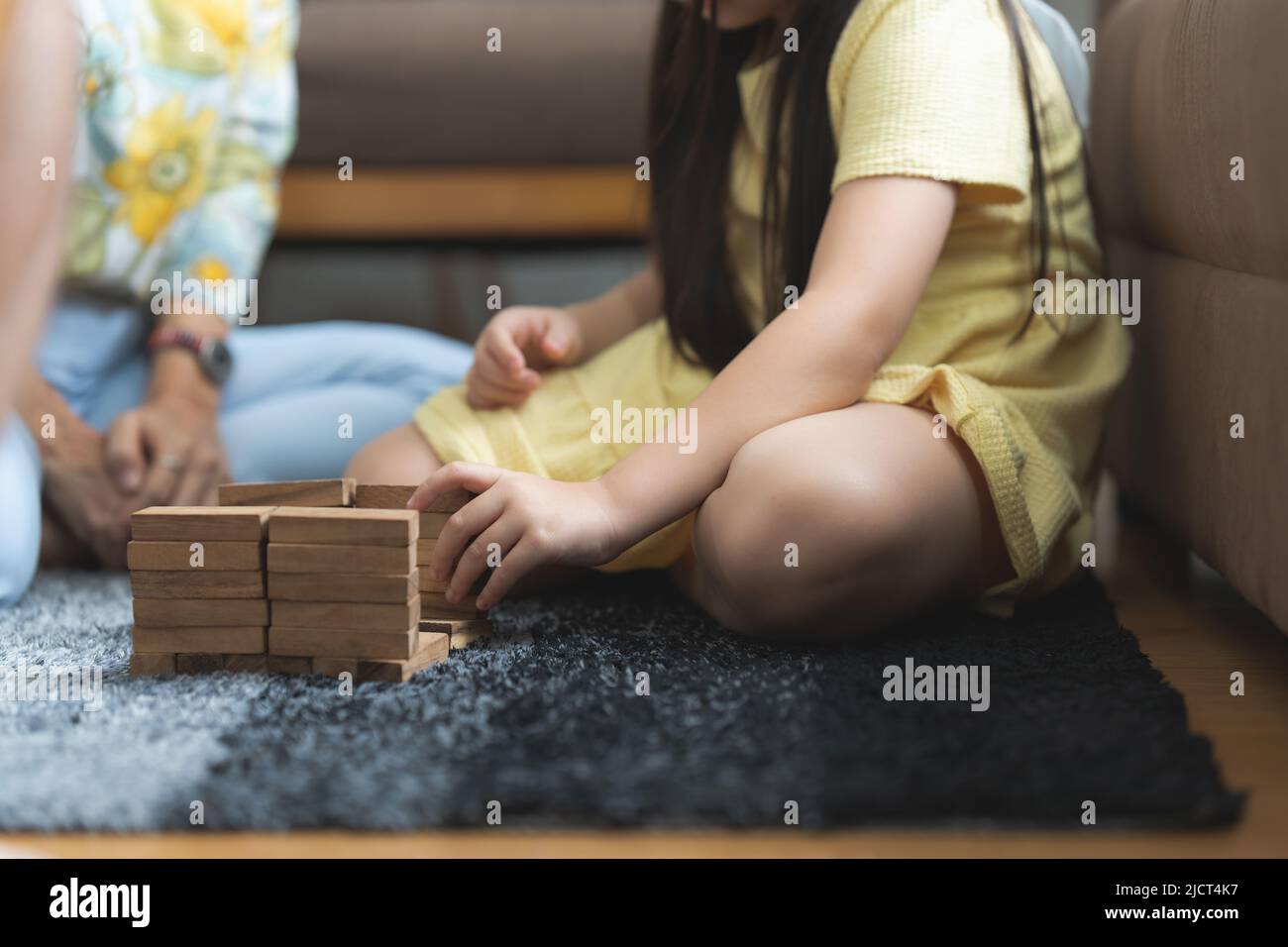 Fille jouant en bois jenga constructeur avec grand-mère à la maison. Activités de loisirs pour les enfants à la maison. Banque D'Images