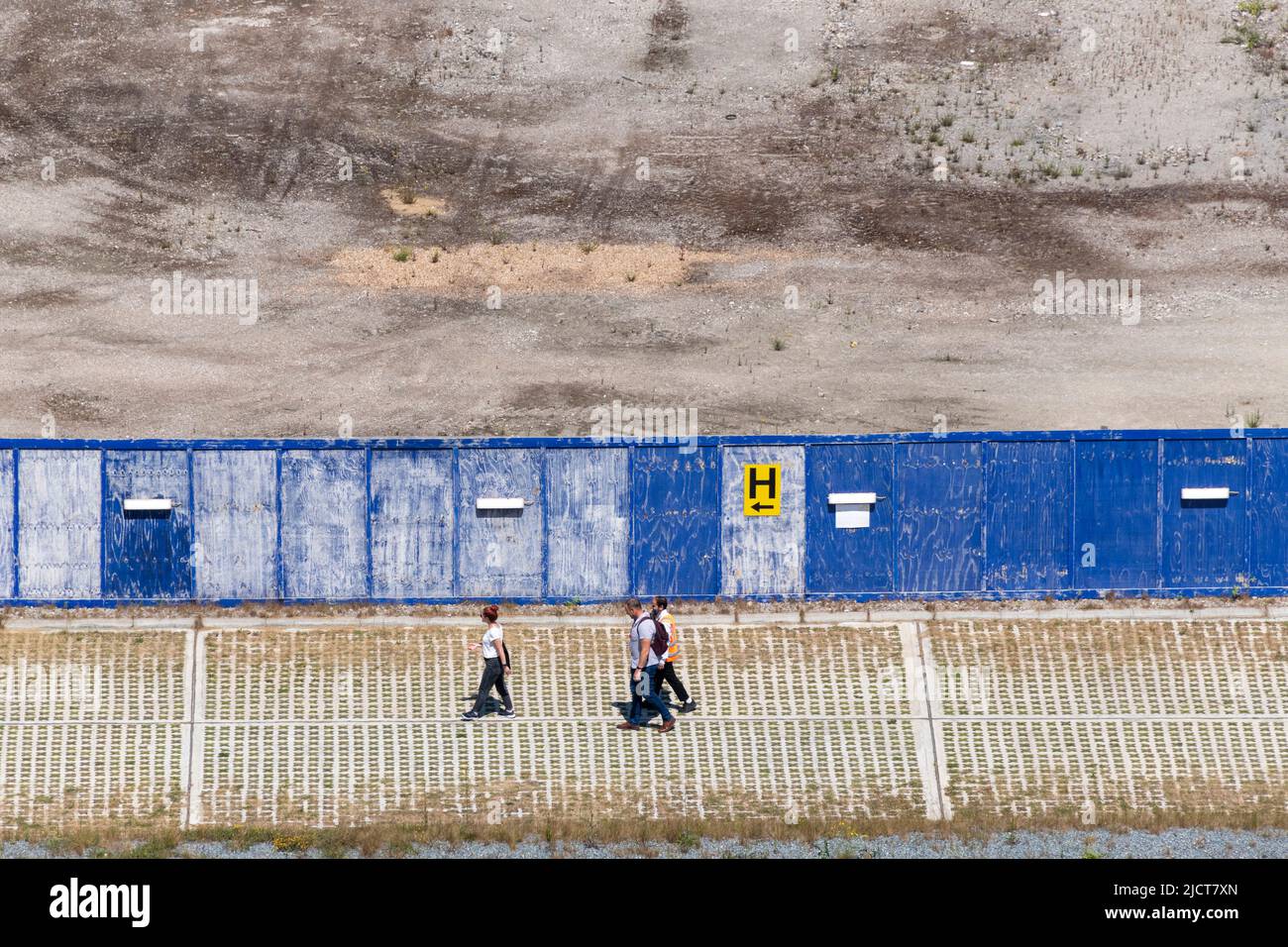 3 personnes marchent devant un site de construction vide dans les Docklands de l'est de Londres. Banque D'Images