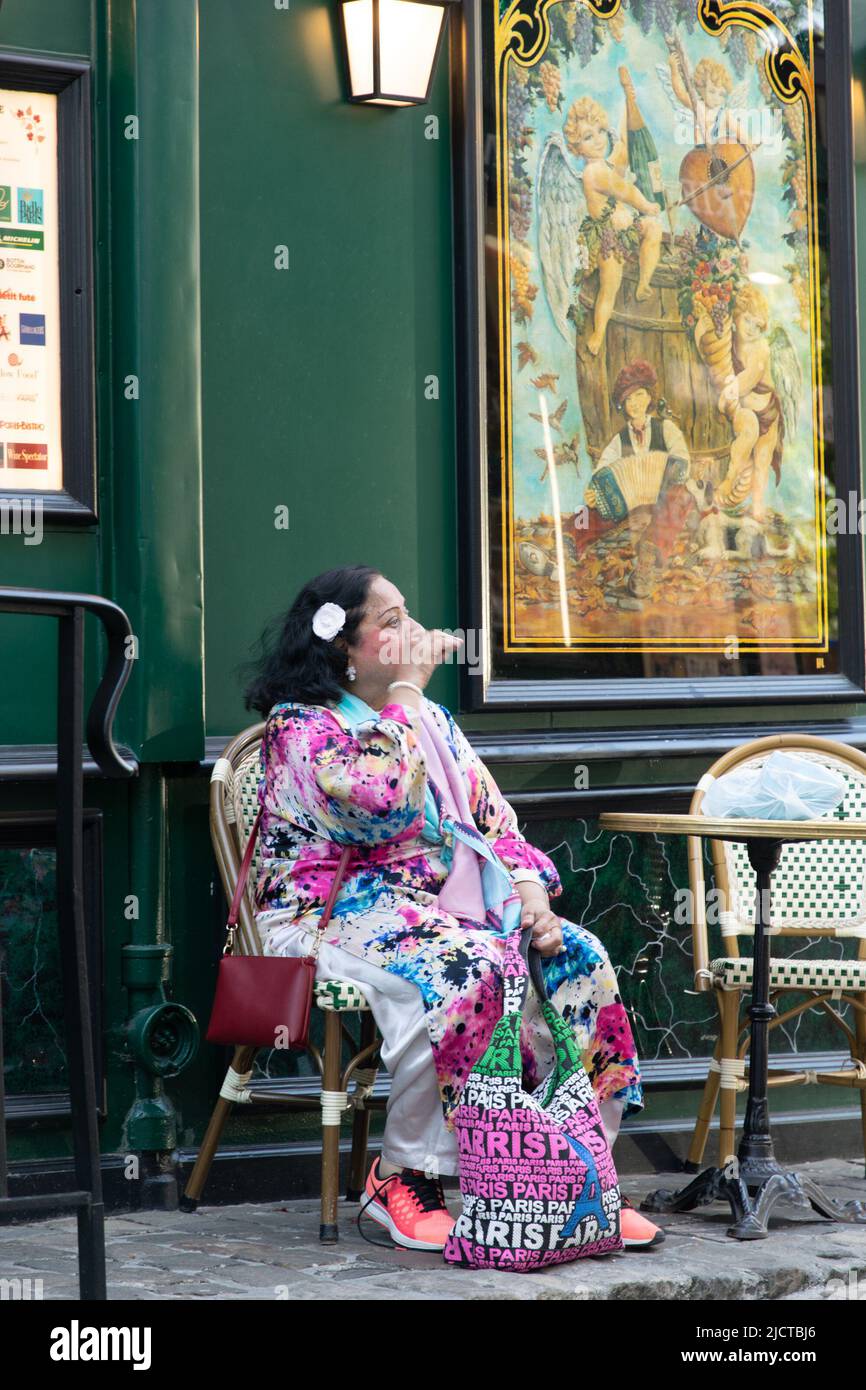 Femme avec robe colorée assis dans un restaurant à Montmartre, Paris Banque D'Images
