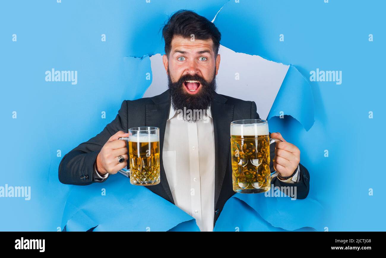 Homme barbu avec une tasse de bière regardant à travers le trou de papier. Lager et ALE sombre. Boissons, alcool, bar. Banque D'Images