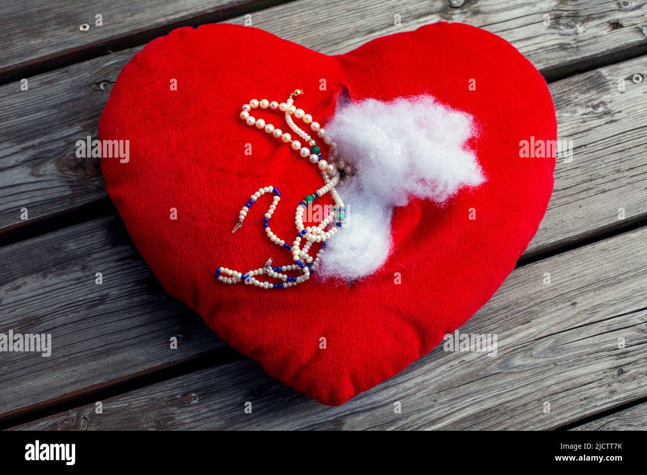 coeur en peluche déchiré rouge avec bijoux sur le sol Banque D'Images