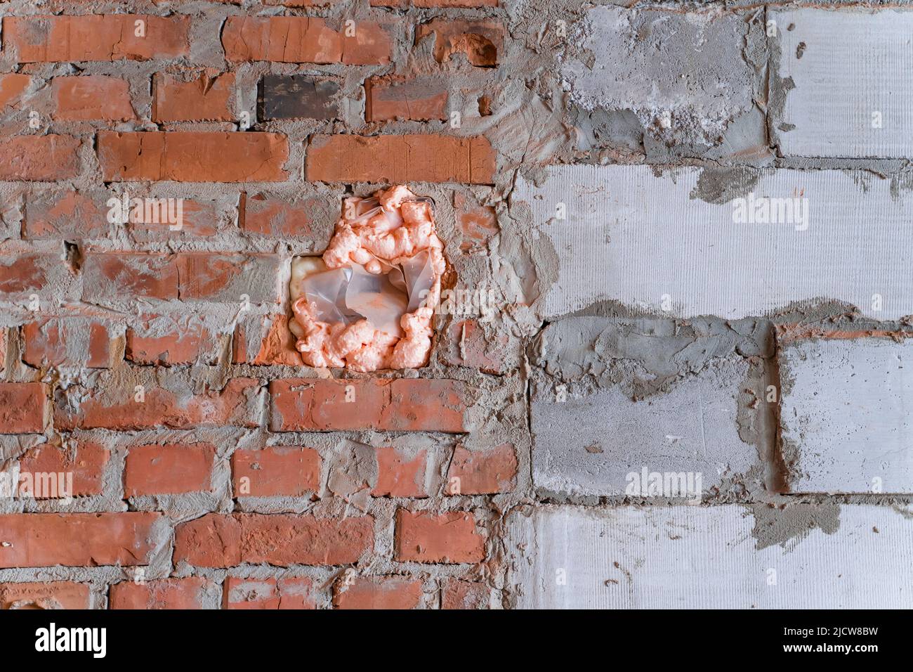 Le trou dans le mur était rempli de mousse. Mur en brique rouge et bloc de  béton cellulaire Photo Stock - Alamy