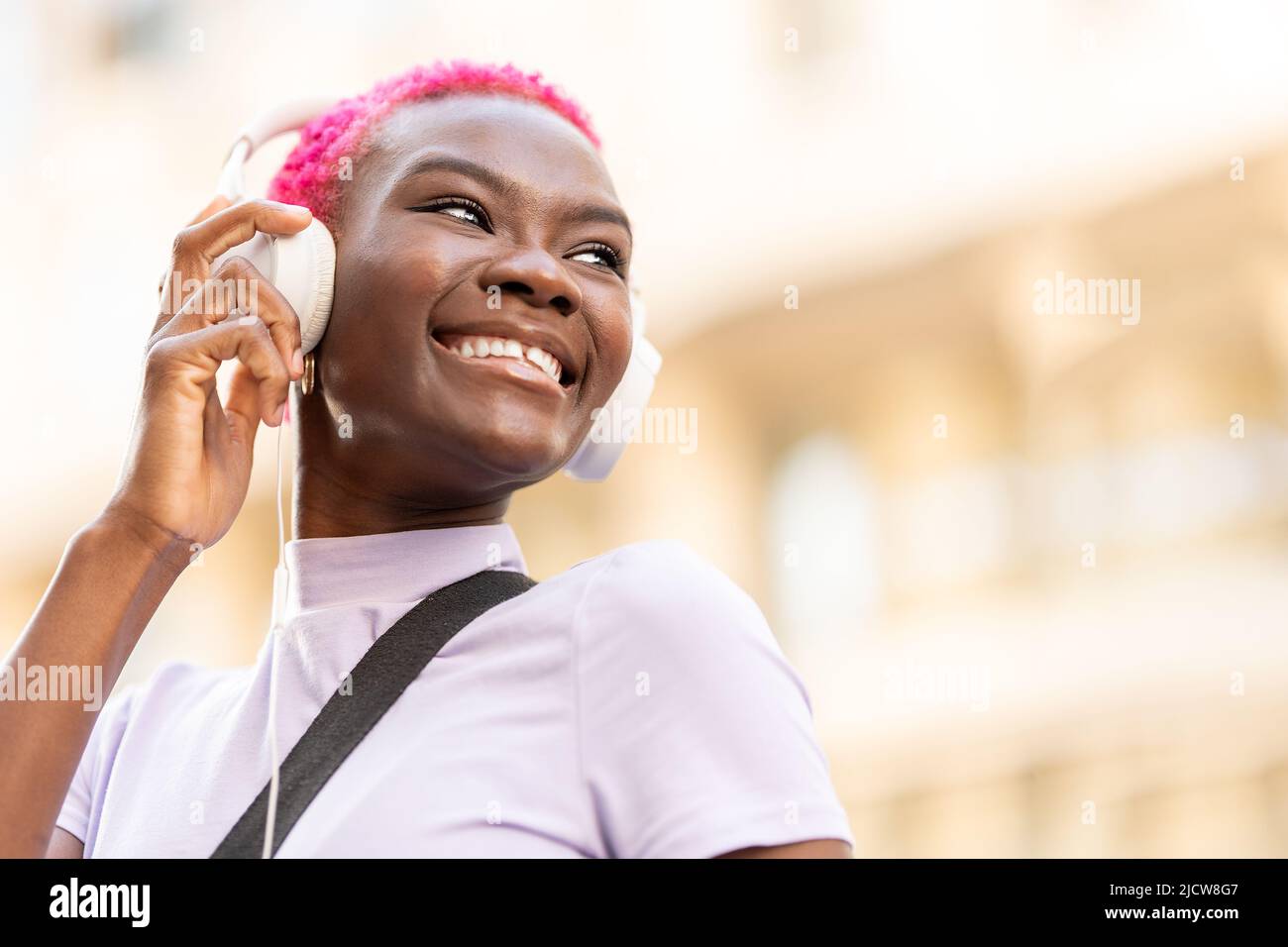 Portrait en vue à angle bas avec espace de copie d'une femme afro souriante utilisant un casque dans la rue Banque D'Images