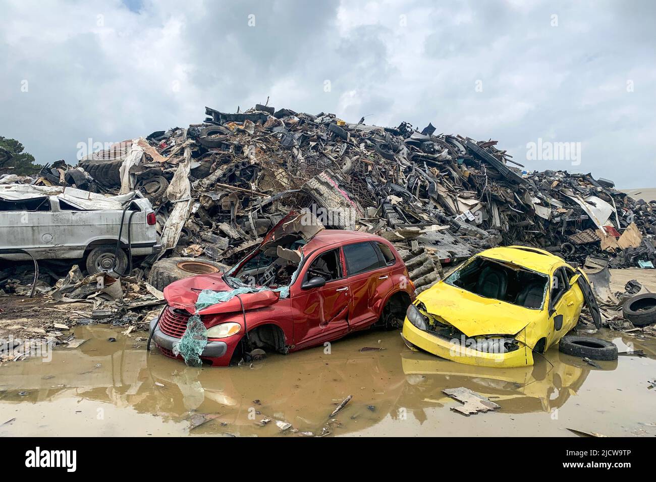 Voiture cassée dans un jardin, ferraille de voiture, vieille automobiles corrodées écrasées empilées dans un cimetière dans la flaque Banque D'Images