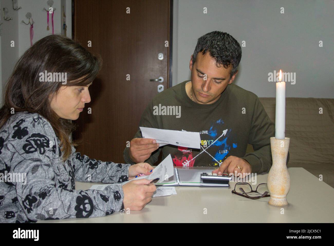 Jeune couple à la maison vérifiant leurs factures récemment arrivées. Référence à l'augmentation actuelle des prix de l'électricité et du gaz naturel Banque D'Images