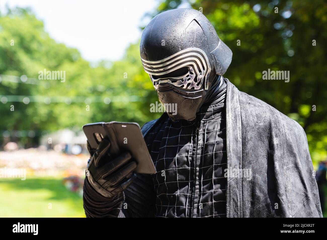 Erlangen, Allemagne. 16th juin 2022. Le cojoueur Frank, ici dans son costume comme le personnage de Star Wars Kylo Ren, regarde son smartphone tout en visitant le Comic salon 2022 à Erlangen. Credit: Nicolas Armer/dpa/Alay Live News Banque D'Images