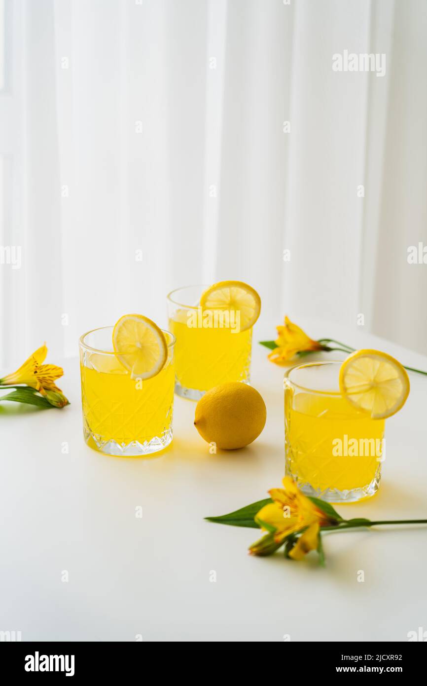 tonique d'agrumes frais près des citrons et des fleurs d'alstroemeria jaunes sur fond blanc Banque D'Images
