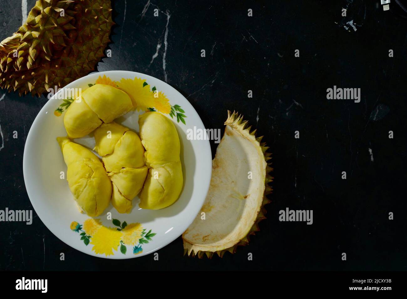 Durian frais en emballage sur un plat blanc avec pelage durian sur fond noir de bannière. Roi durien des fruits. Fruits tropicaux. TopView de durien mûr Banque D'Images