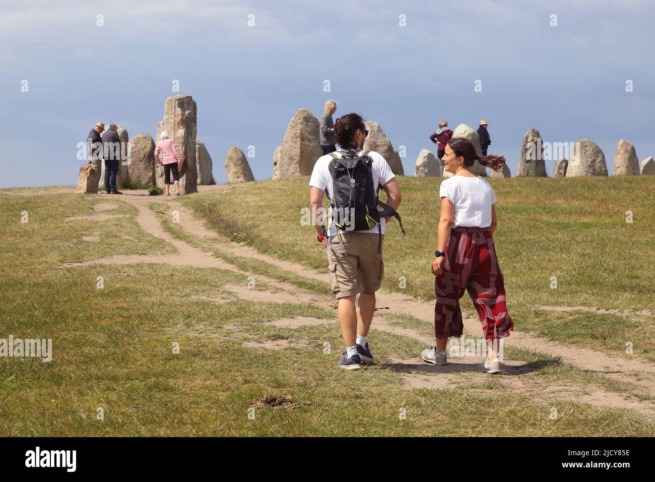 Kaseberga, Suède - 15 juin 2022: Un couple marchant sur le chemin de pied à l'anicient navire de pierre monument Ales pierres. Banque D'Images