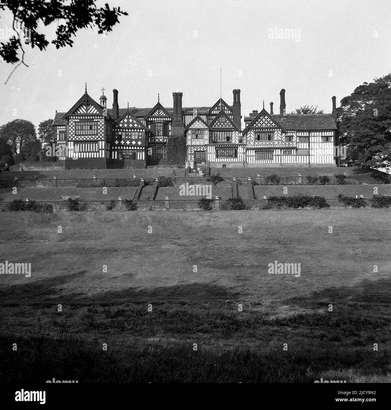 1940s, historique, vue du parc en haut, de Bramall Hall, Bramhall, Stockport, Angleterre, ROYAUME-UNI. Un manoir Tudor à pans de bois qui date du 14th siècle, avec plus tard des ajouts, la maison et le parc environnant ont été acquis par les autorités locales en 1935 et sont devenus un musée. La famille Davenport, qu'on croit construire la maison, a tenu le manoir pendant plus de 500 ans. Banque D'Images