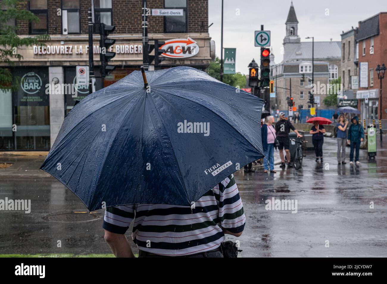 Montréal, CA - 12 juin 2022 : personnes sur l'avenue Mont-Royal tenant un parapluie sous la pluie et la tempête Banque D'Images