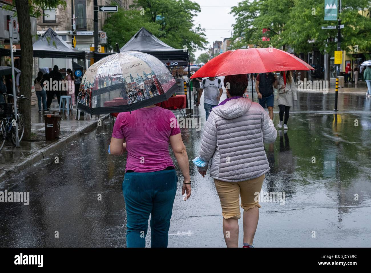 Montréal, CA - 12 juin 2022 : personnes sur l'avenue Mont-Royal tenant un parapluie sous la pluie et la tempête Banque D'Images
