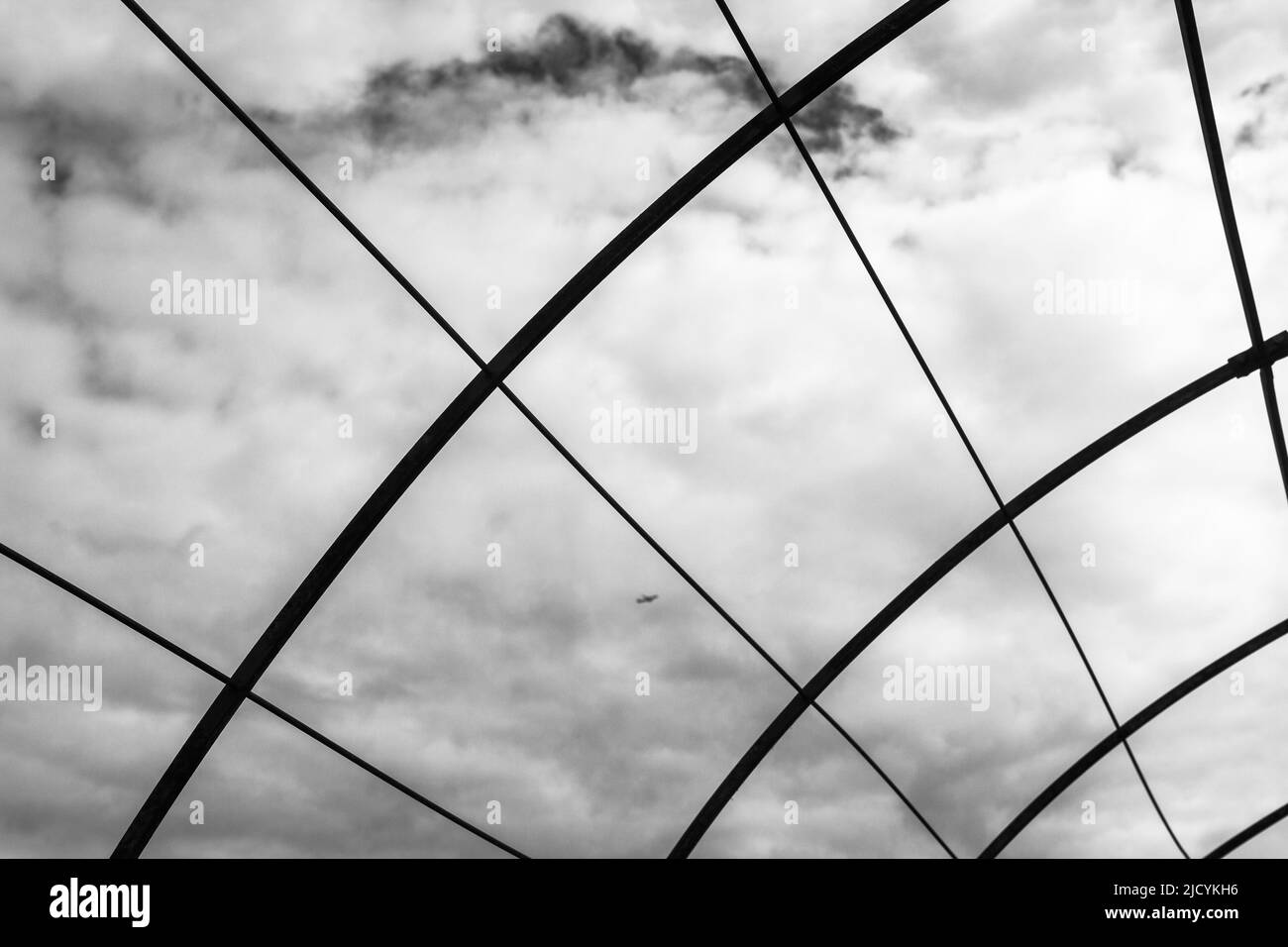 Une image en noir et blanc du cadre métallique d'une maison agricole de cerceau ou d'un polytunnel. Banque D'Images