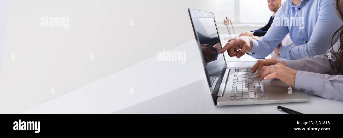 Close-up of Business People Working On Laptop At Desk In Office Banque D'Images