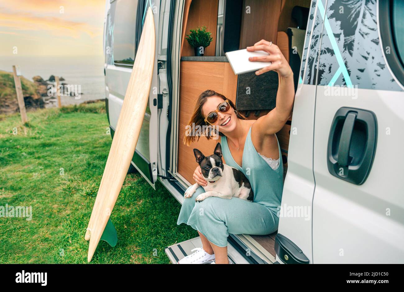 Femme prenant des photos assis avec son chien à la porte de la camionnette de camping Banque D'Images