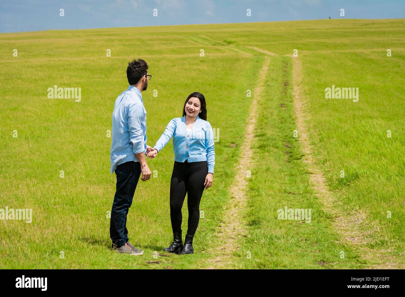 Deux personnes tenant les mains dans le champ, beau couple tenant les mains regardant l'un l'autre dans le champ, deux amoureux dans le champ tenant les mains Banque D'Images