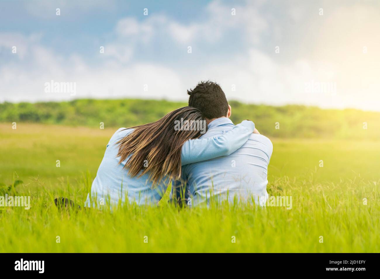 Couple romantique assis sur l'herbe embrassant de l'arrière, vue arrière d'un couple amoureux embrassant sur l'herbe, Un couple amoureux assis sur l'herbe Banque D'Images