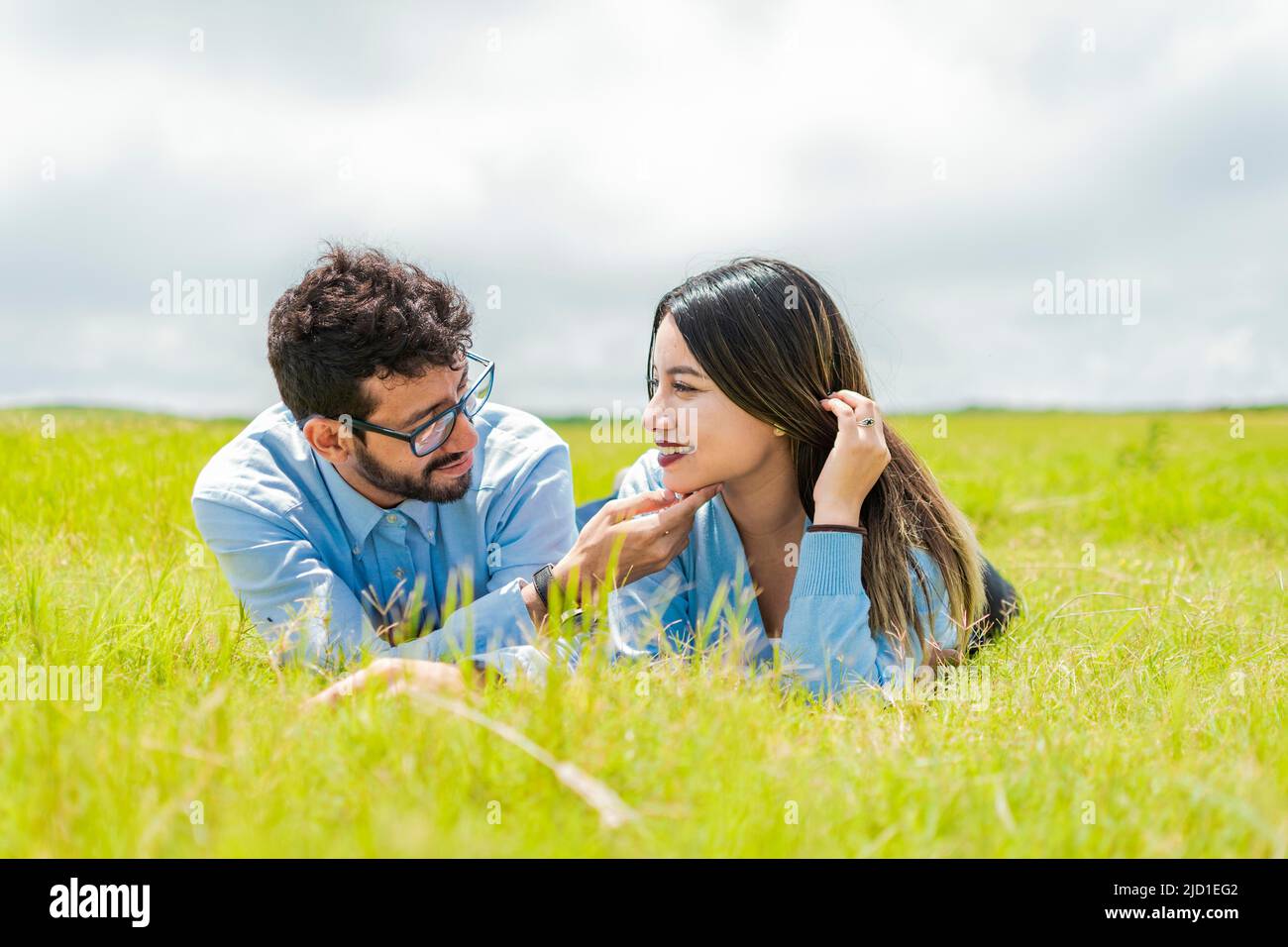 Un jeune couple amoureux allongé sur l'herbe se touchant les visages de l'autre, deux personnes amoureux allongé sur l'herbe se regardant l'une l'autre, Un couple couché Banque D'Images