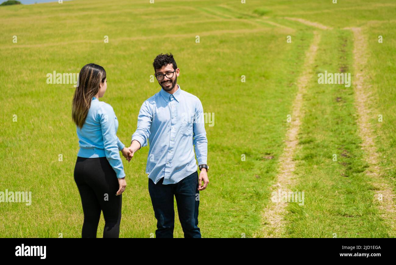 Deux amoureux souriants dans le champ tenant les mains, beau couple tenant les mains regardant l'un l'autre dans le champ, deux personnes tenant les mains dans le Banque D'Images