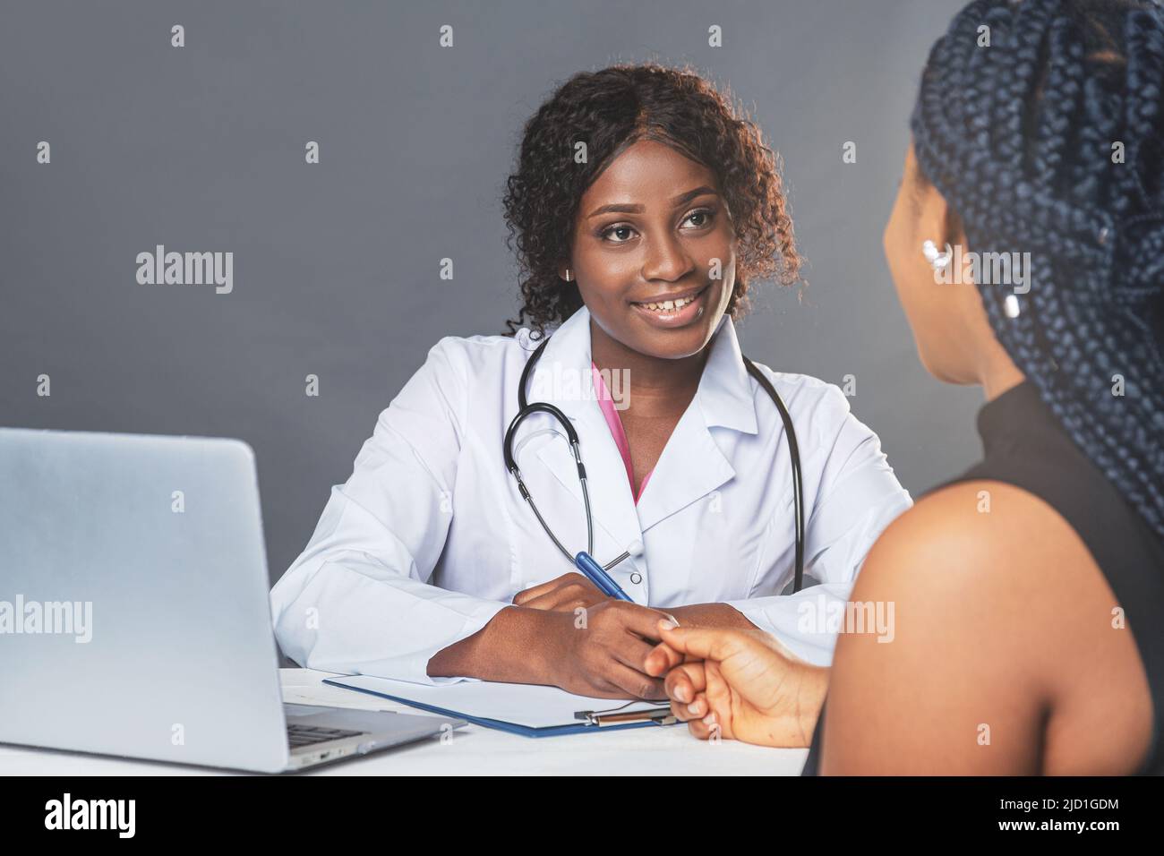 Femme afro-américaine médecin en cabinet médical avec un patient tout en portant un masque de protection pendant un rendez-vous médical Banque D'Images